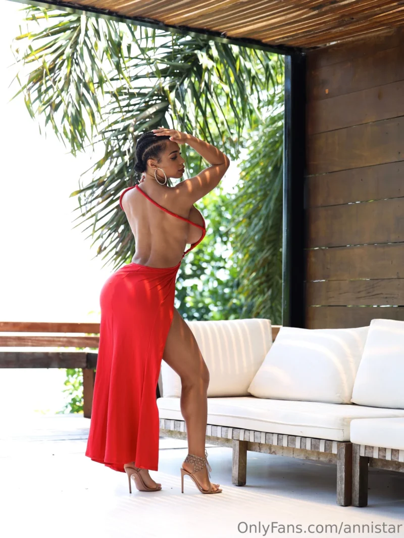 Naughty Anni Star in red backless dress posing by white couch with palm trees