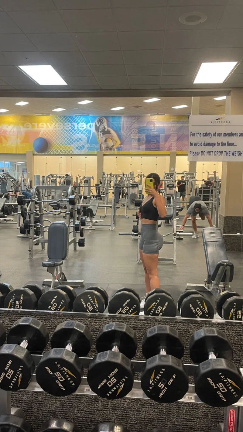 Sultry Angela Alvarez in gym shorts and sports bra taking mirror selfie, porn photo
