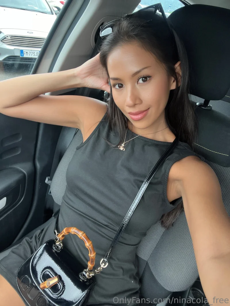 Curvy Nina cola in black dress posing in car with hand on head
