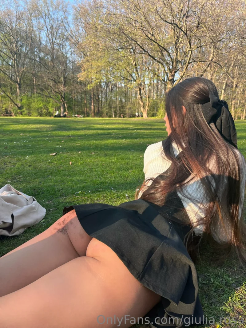 Sultry Giulia Rosa sitting on grass in schoolgirl outfit, skirt hiked up showing ass