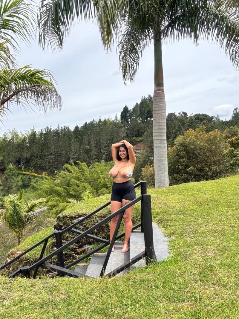 Naughty Dasani Delgado in black shorts and bikini top poses on outdoor steps with palm trees