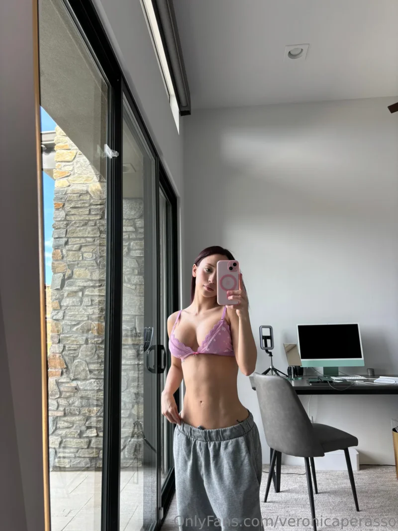 Flirty Veronica Perasso in pink bra and grey sweats takes a mirror selfie by the glass door