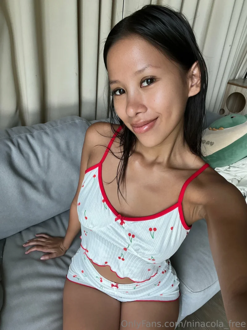 Seductive Nina cola in cherry print lingerie smiles at camera on gray couch