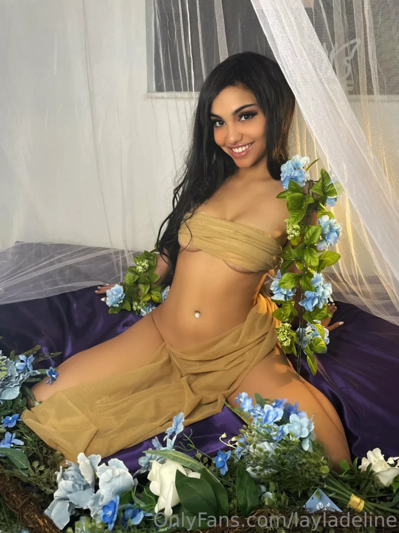 Busty Layla Deline in gold wrap posing nude with blue flowers on purple sheets