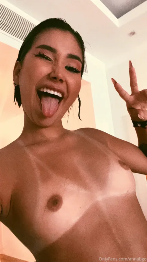 Naughty Anna Beggion topless with tongue out and peace sign in a room